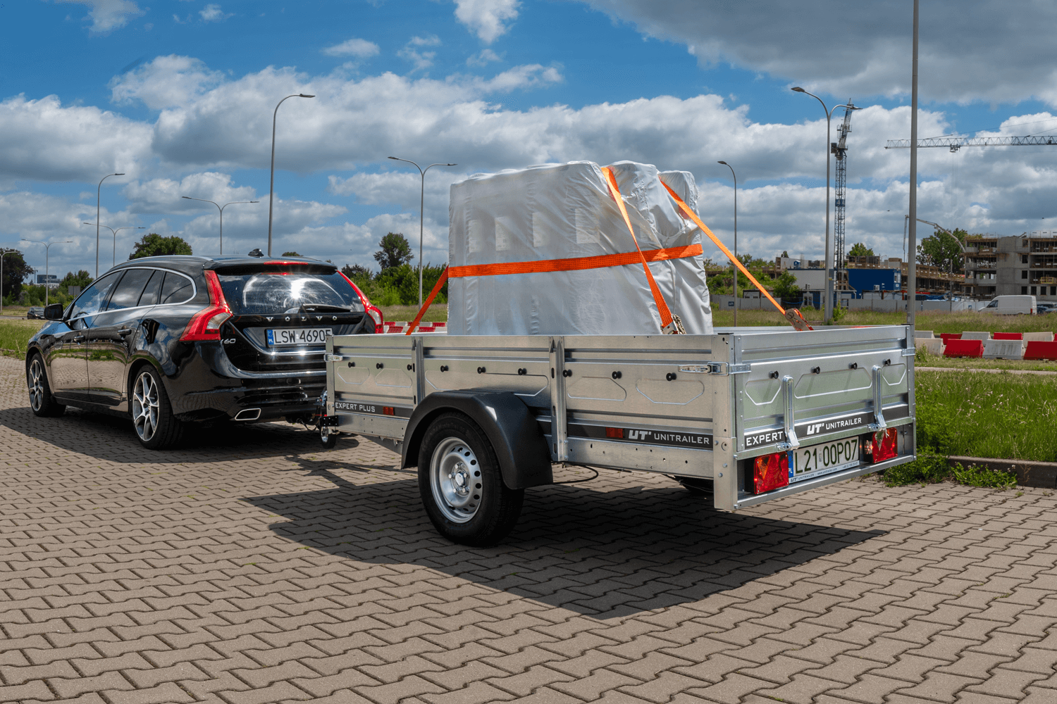 Volvo V70 w kolorze czarnym holujące przyczepkę z zamocowanym pionowym ładunkiem